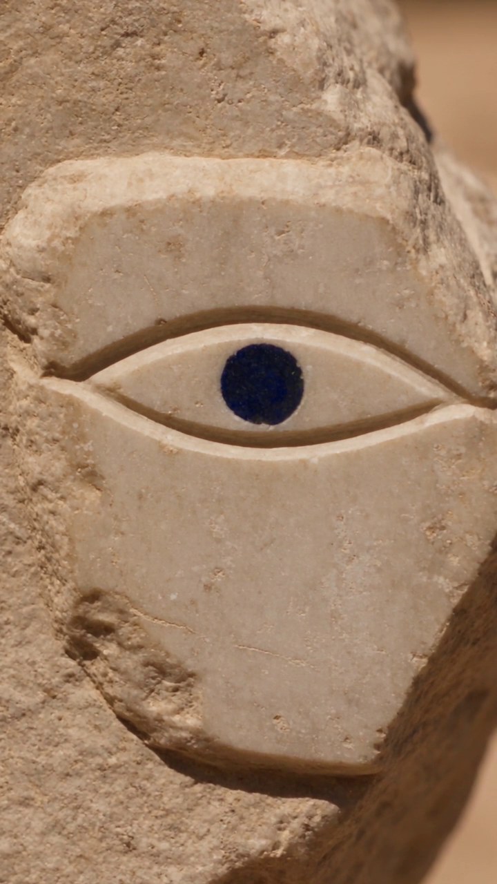 A carved stone face with a cobalt iris.